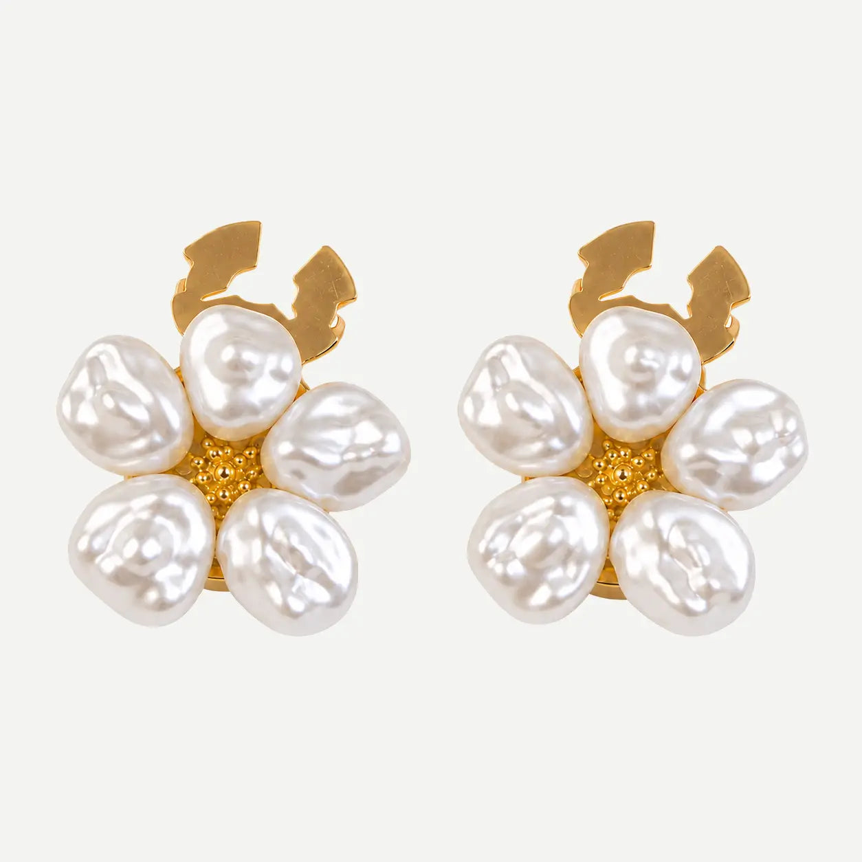 A pair of gold and pearl flower-shaped earrings on a light gray background.